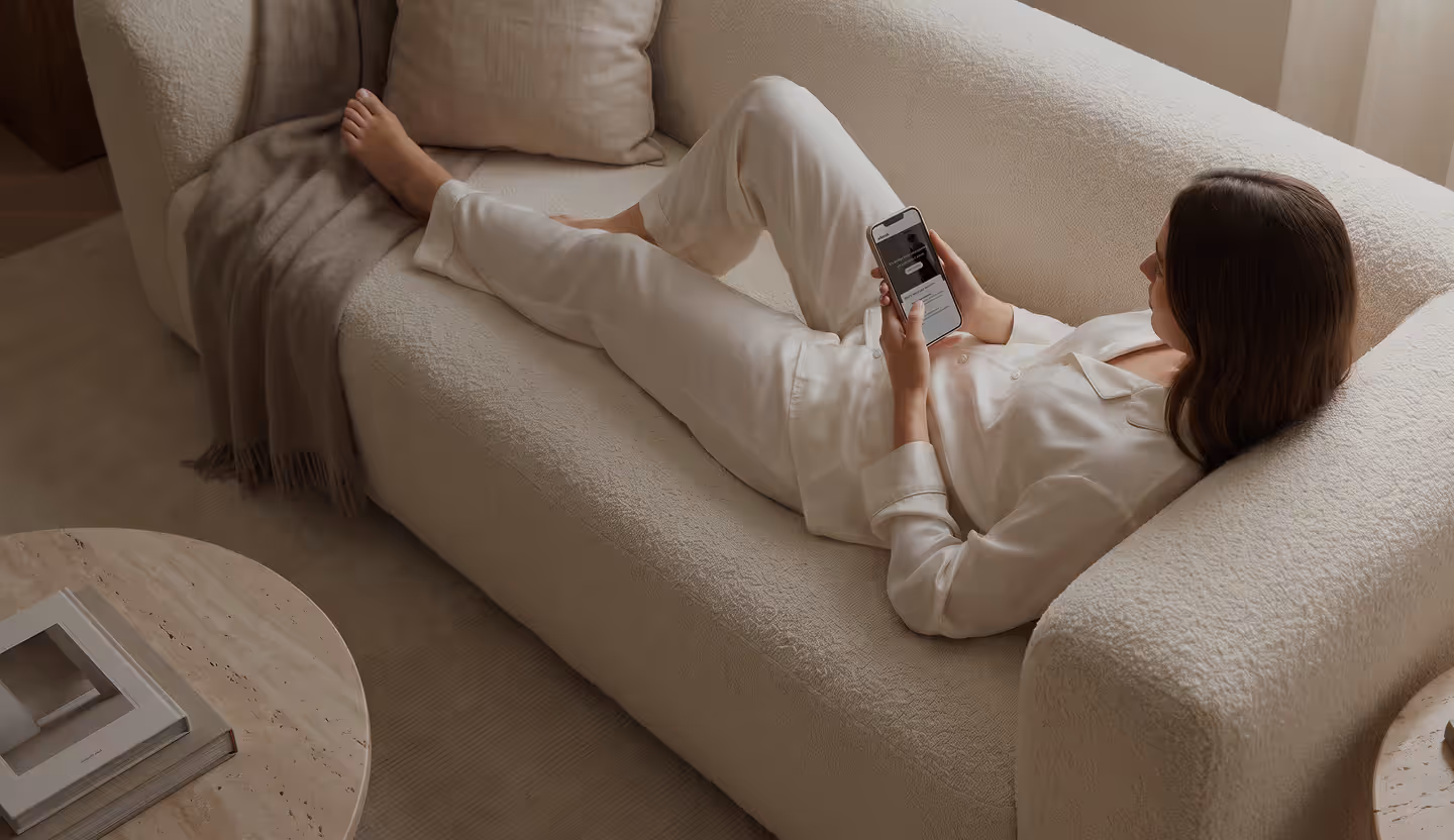 Woman relaxing on a sofa, starting a consultation on her phone