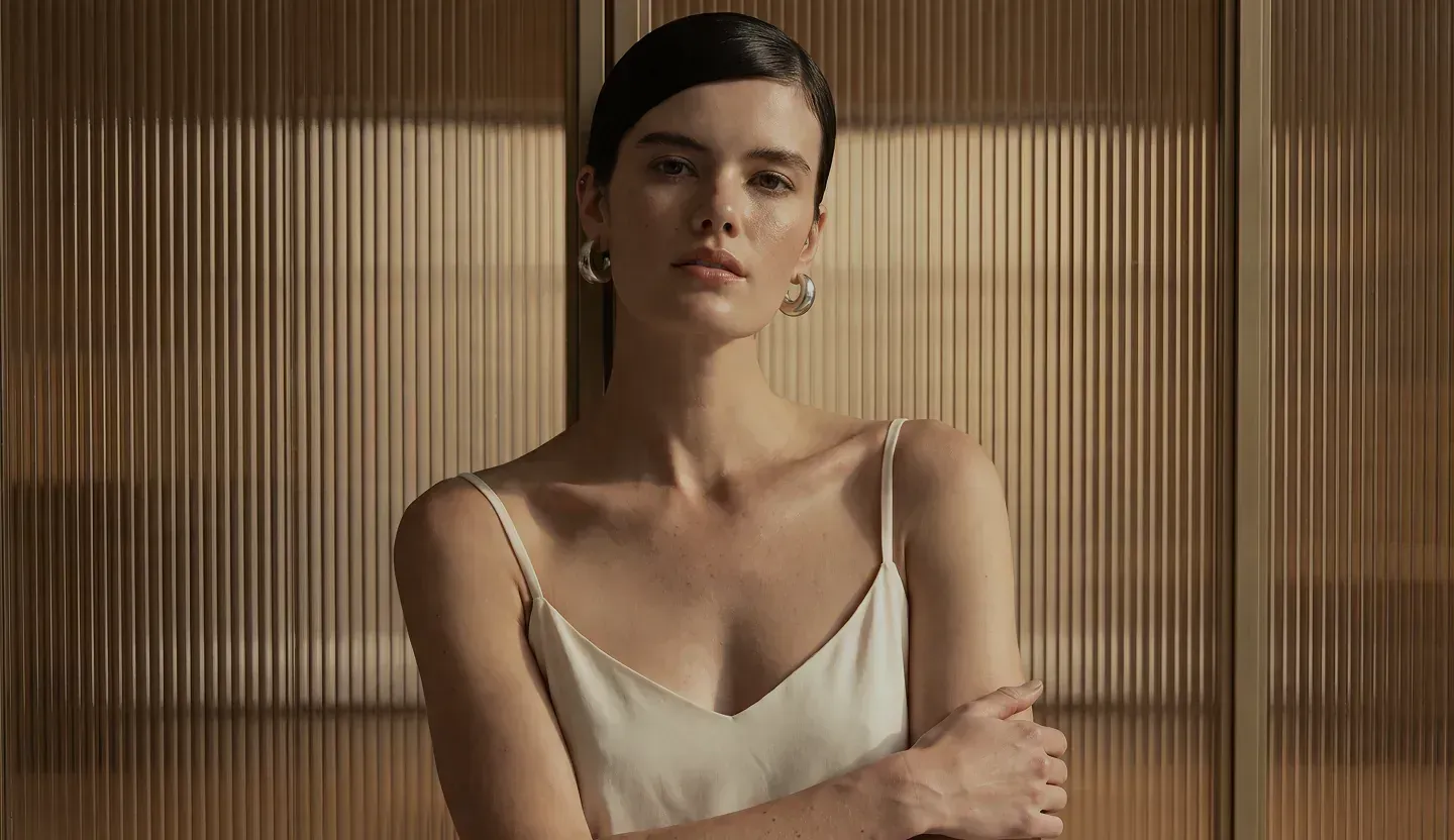 Woman in a light-colored swimsuit by a window – breast surgery at Skulpturkliniken