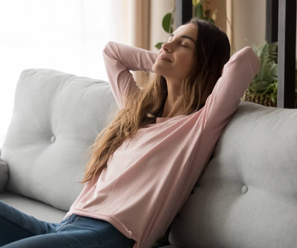 A mother settling in for a restful, propped-up recovery day at home after a mommy makeover.