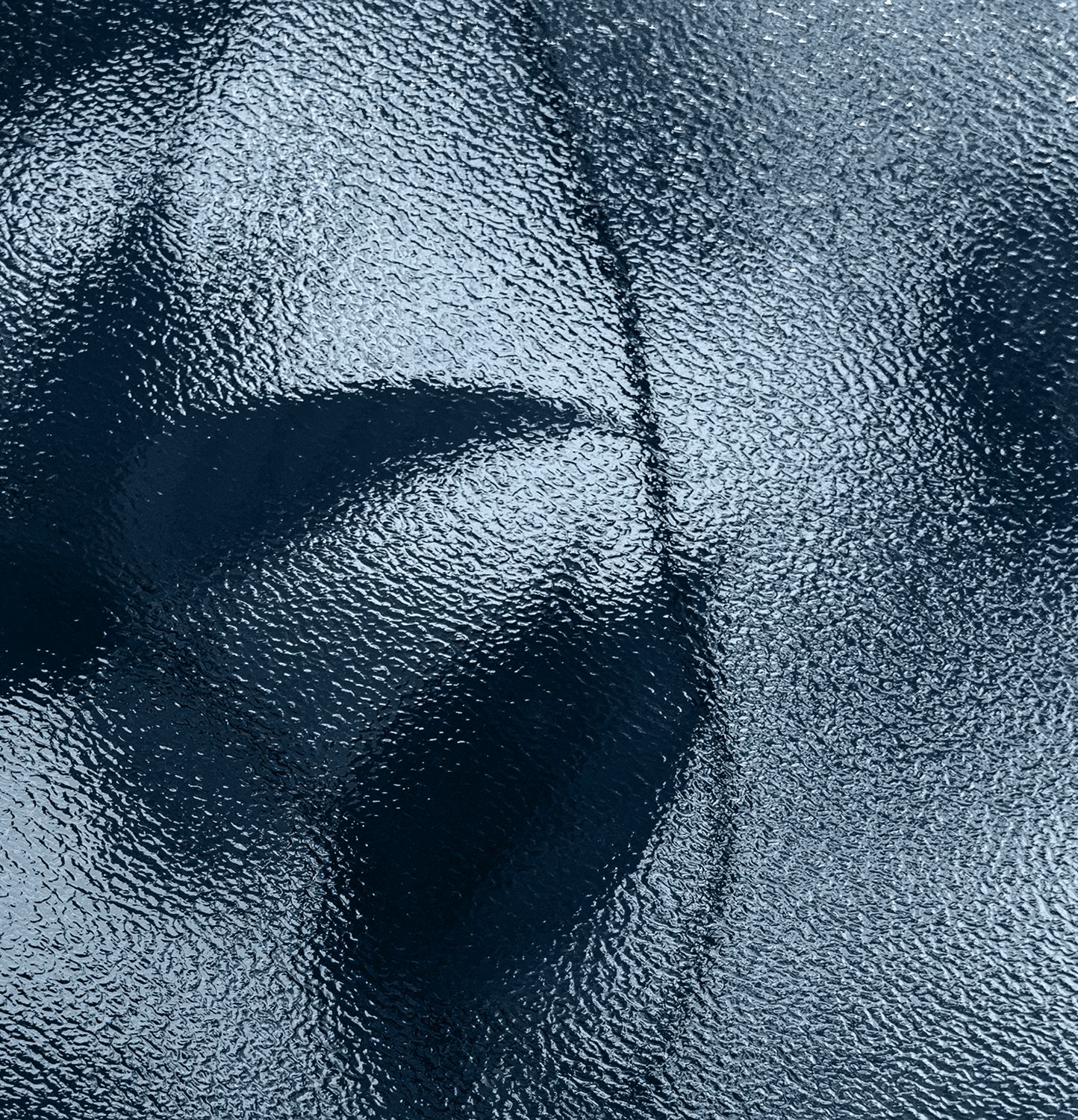 A close-up image showing a textured surface that resembles frosted glass, with light and shadow creating a sense of depth and pattern.