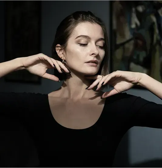 Woman in a black top with her hands near her face