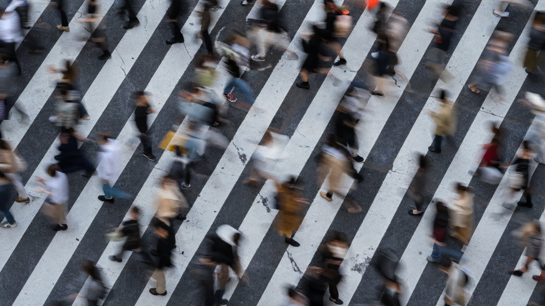 A crowd crossing a city street — background image behind the homepage's 'Why we exist' patient-concerns section.