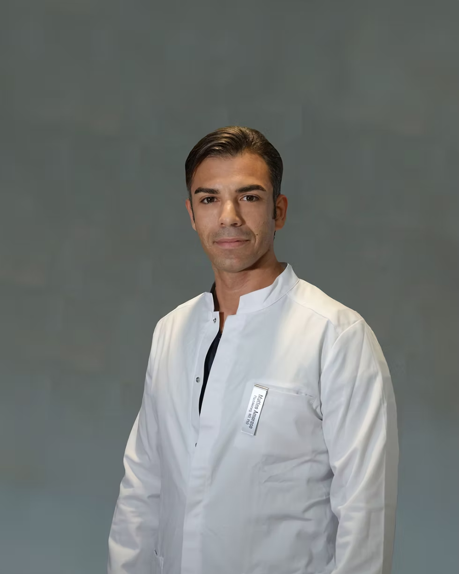 Dr. Matteo Amoroso in a white clinical coat against a grey-green wall.