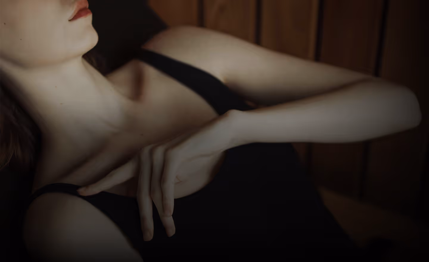 A close-up of a person in a black tank top resting their hand on their shoulder, with a focus on the neckline and hand position.