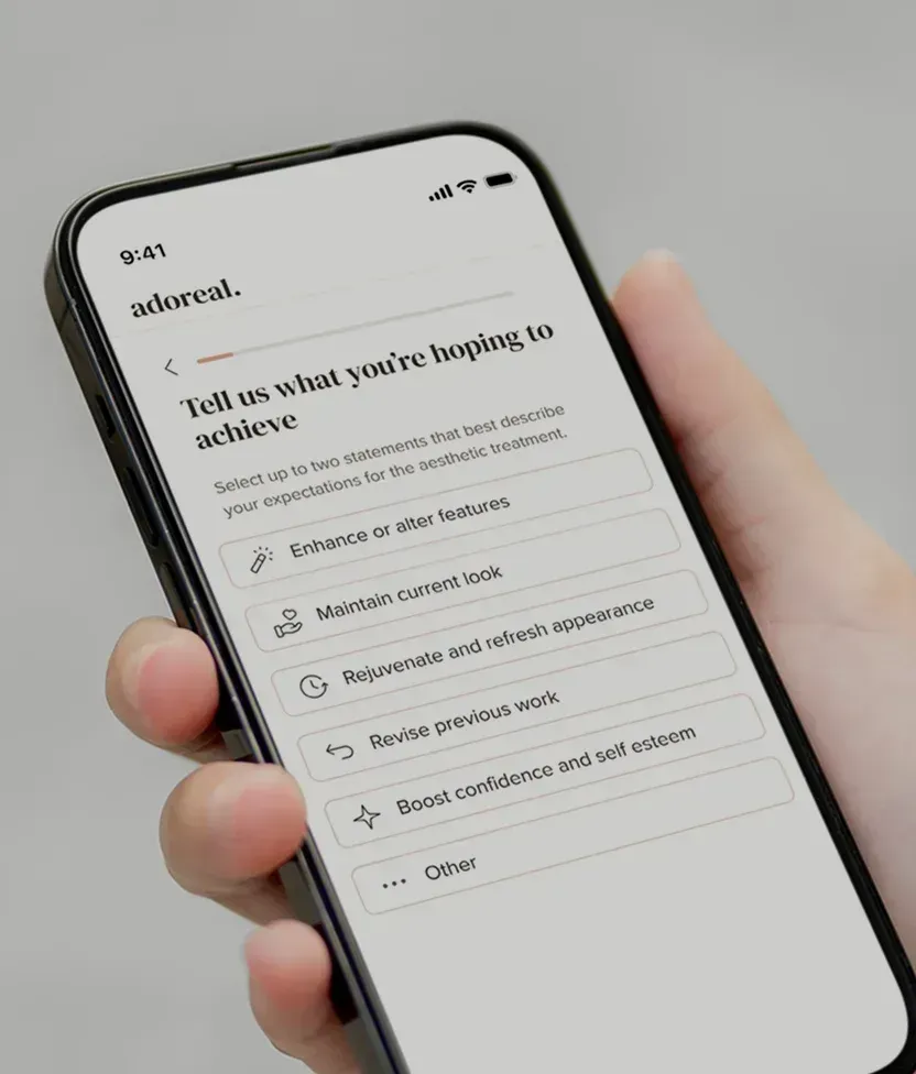 Hand som håller en mobiltelefon med Adoreals konsultationsformulär