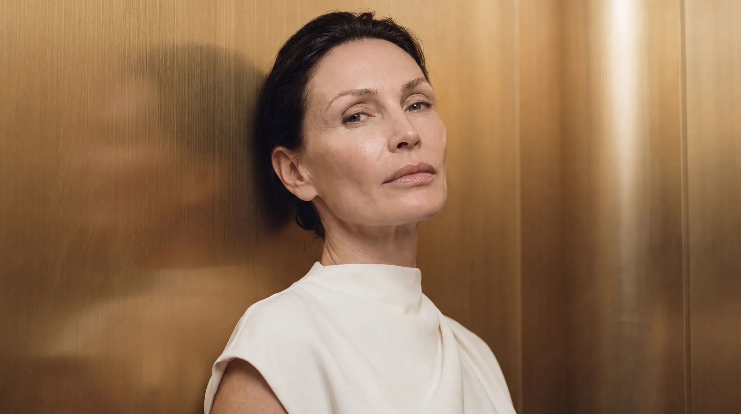 Woman looking in a mirror in a bright room – injectable treatment at Skulpturkliniken