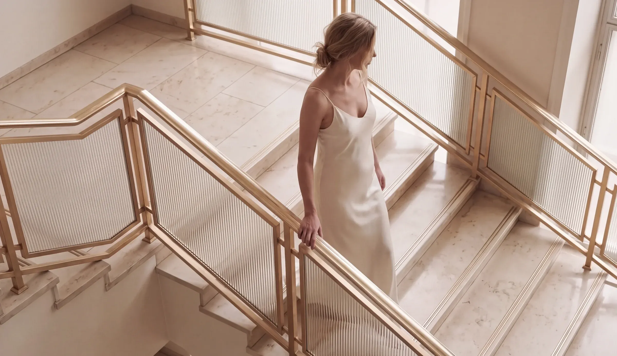 Woman in a slip dress walking down a marble staircase