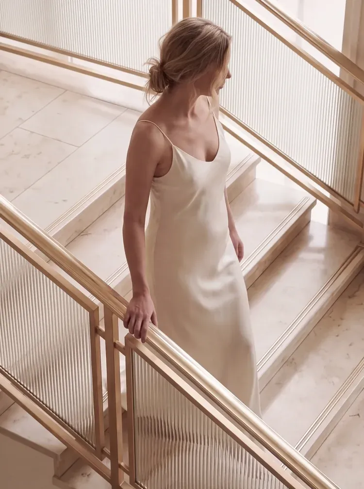 Woman in a slip dress walking down a marble staircase