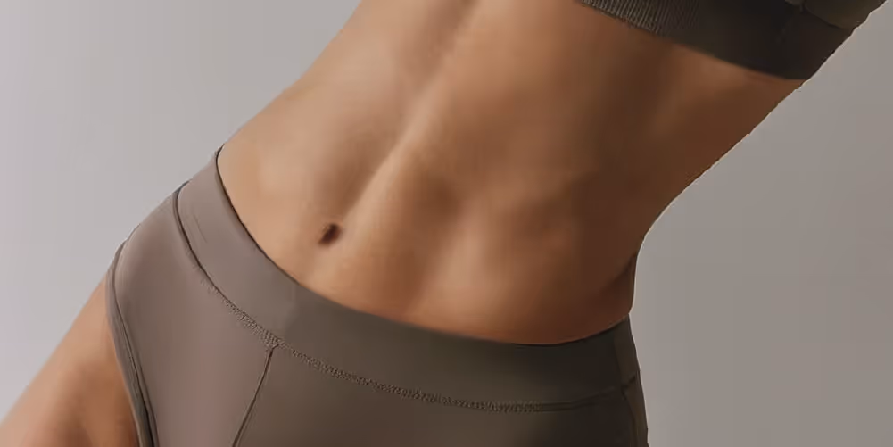 A close-up image of a toned abdominal area, showcasing defined muscles and a navel, contrasted with athletic apparel.